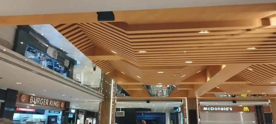 Stepped wooden slatted ceiling at the edge of the mall atrium above restaurant fronts