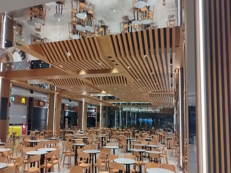 Chairs reflected in the mirrored ceiling beside wooden slats and a slat-clad column