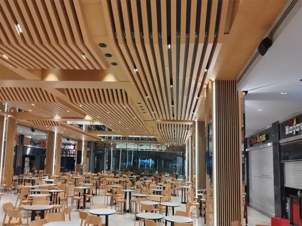 Spotlit wooden slatted ceiling and column cladding next to shuttered shopfronts