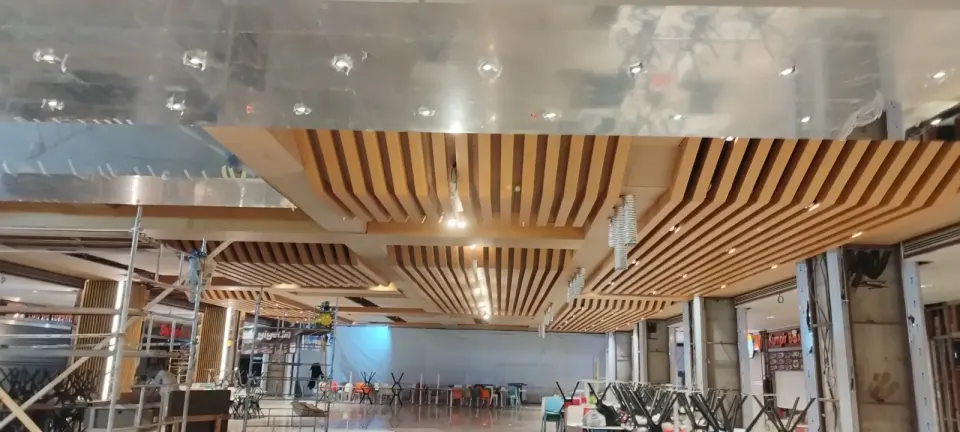 Slatted ceiling modules and a reflective metal surface in the food court under construction